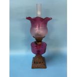 An oil lamp, with cranberry shade and reservoir