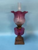 An oil lamp, with cranberry shade and reservoir