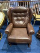 A brown leather wing armchair