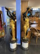 A large pair of modern bronze Blackamoors, of two ladies holding aloft baskets, signed Milo,