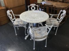 A metalwork patio table and four chairs, with cushions