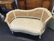 A Bergere double cane two seater settee, with cream distressed frame, 132cm wide, 65cm deep approx.