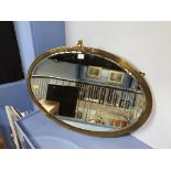 A heavy brass oval mirror, 73cm wide