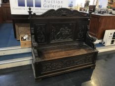 A late 19th century to early 20th century carved oak settle
