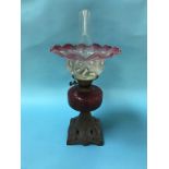 An oil lamp with cranberry and opaque crimped shade and cranberry reservoir