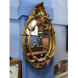 An ornate gilt oval mirror, 103 x 60cm