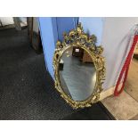 A gilt ornate oval mirror, 97 x 57cm