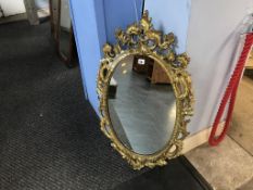 A gilt ornate oval mirror, 97 x 57cm