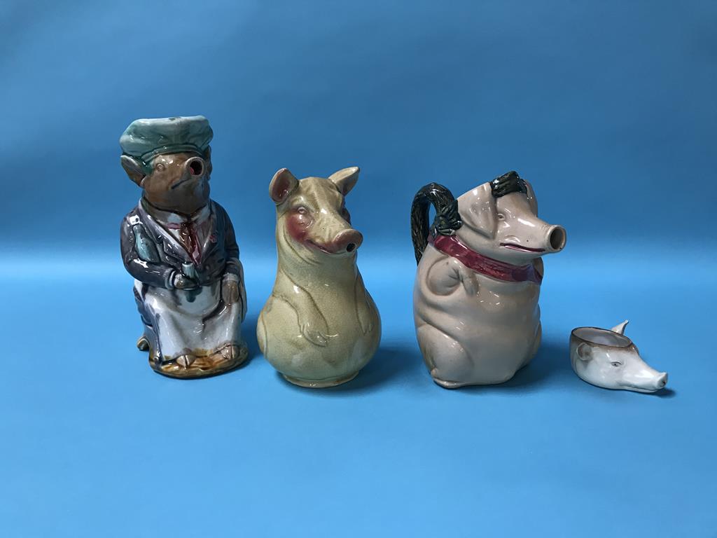 A French majolica water jug in the form of a dressed seated pig and three other pig form jugs (4)