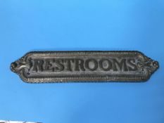 A heavy brass sign 'Restrooms', 56cm long