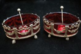 Pair of silver salts with cranberry glass liners and spoons, Birmingham 1902 (some loss to one, see