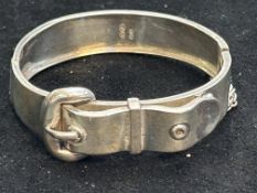 Silver bangle in form of a belt with safety chain