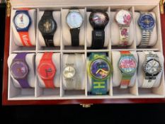 Collection of 12 Swatch watches in display case
