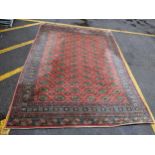 A Middle Eastern machine woven red ground rug having repeating motifs and multiguard borders,