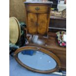 An early 20th century oak oval wall hanging mirror, together with a walnut bedside cabinet