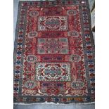 Iranian hand woven red ground rug, three rectangular central panels with stylized birds and