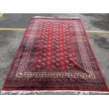 A hand woven Pakistan red ground rug having elephant feet motifs with multiguard borders, 286 cm x