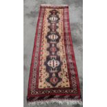 A hand woven Middle Eastern red and beige ground runner having geometric designs and fringed ends,
