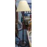 A mid 20th century mahogany standard lamp with a turned column and on three bun shaped feet
