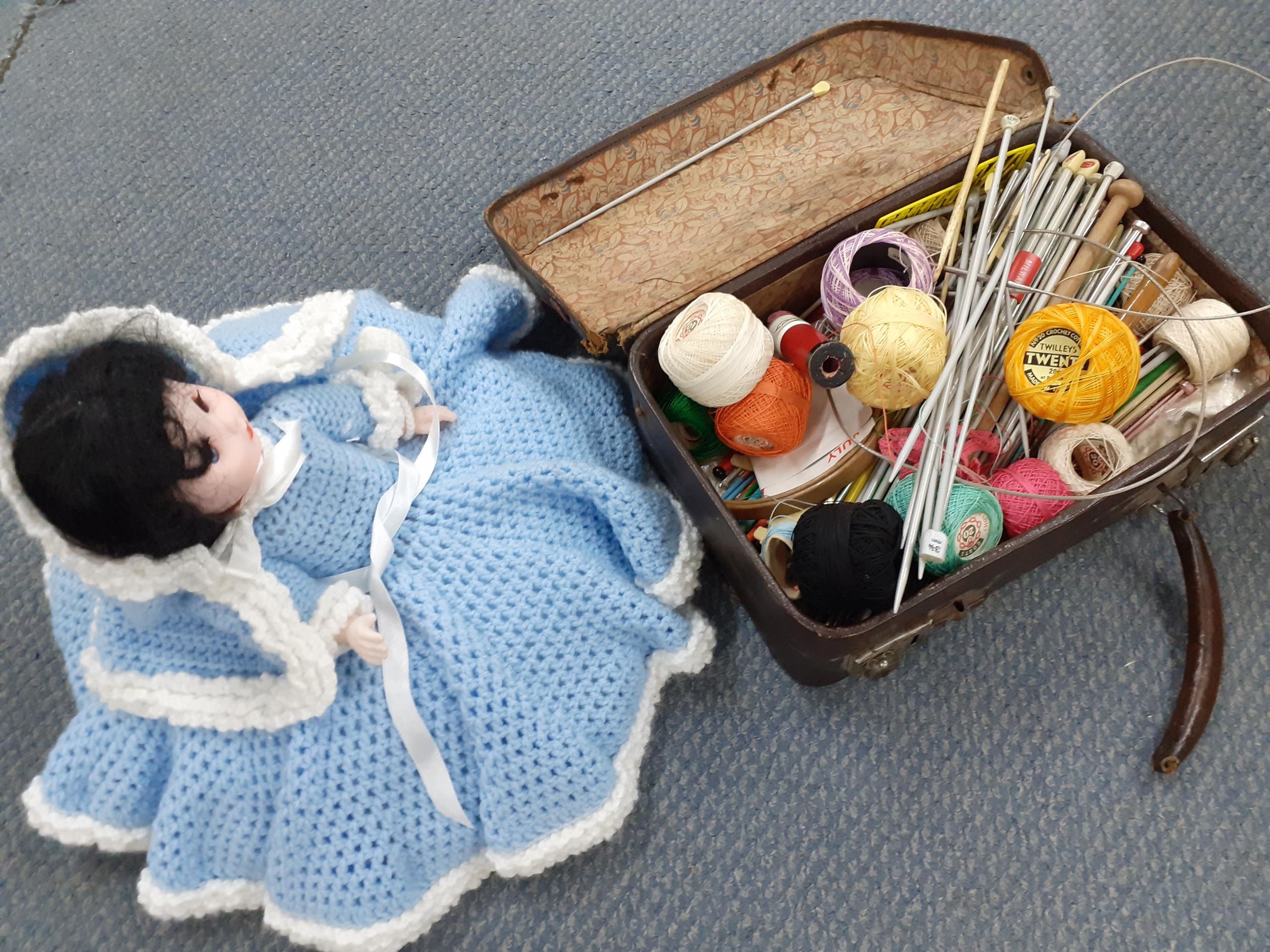A small knitted case with needles and reels together with a 1970's bed dolly in knitted outfit