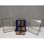 A pair of silver plated easel back photograph frames, a set of fish knives and forks, along with