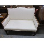 An Edwardian inlaid mahogany salon sofa upholstered in white fabric on square tapering legs and