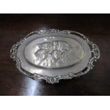 An Edwardian VII silver oval dressing table box, repoussé decorated with winged heads to the lid