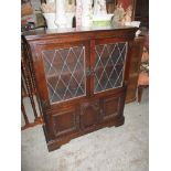 An oak side cabinet, twin leaded display doors with interior adjustable shelf above twin cupboard