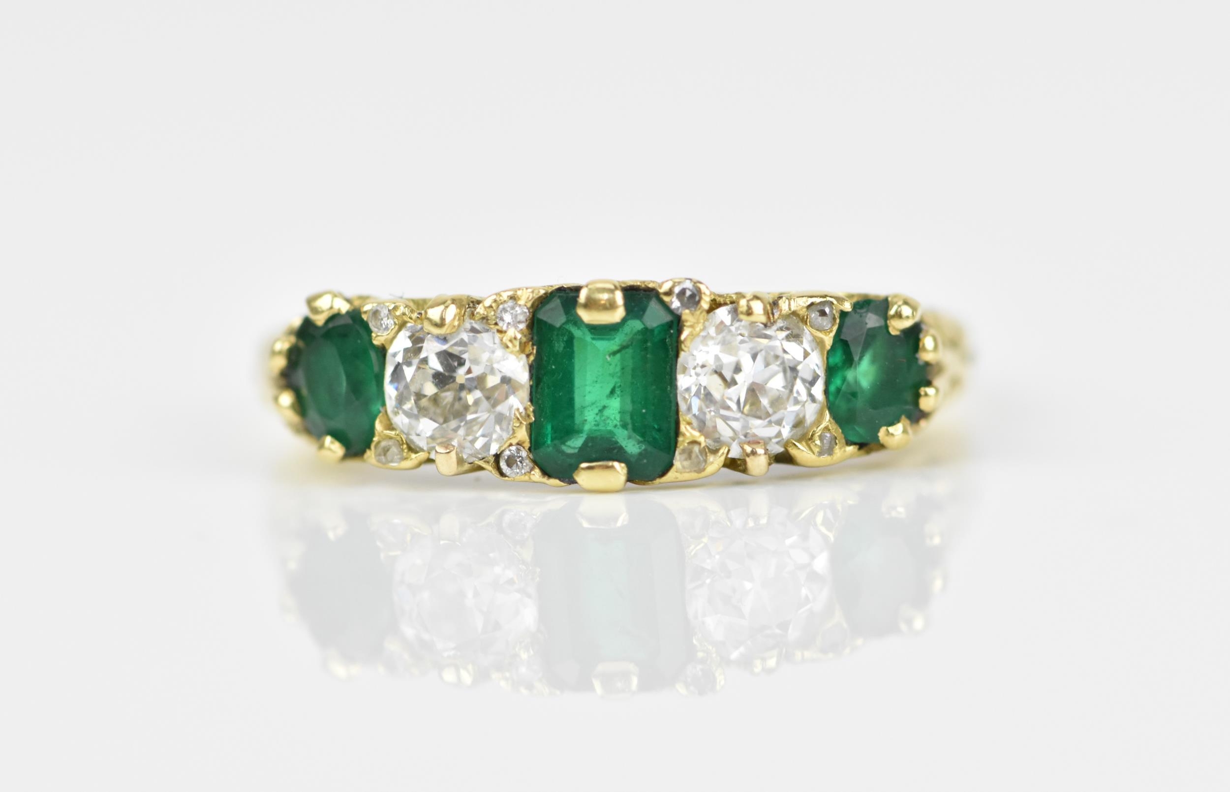 A yellow metal, diamond and emerald five stone ring, set with central octagon cut emerald flanked