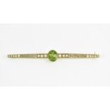 A large yellow metal, seed pearl and green stone bar brooch, the central rub over set stone possibly