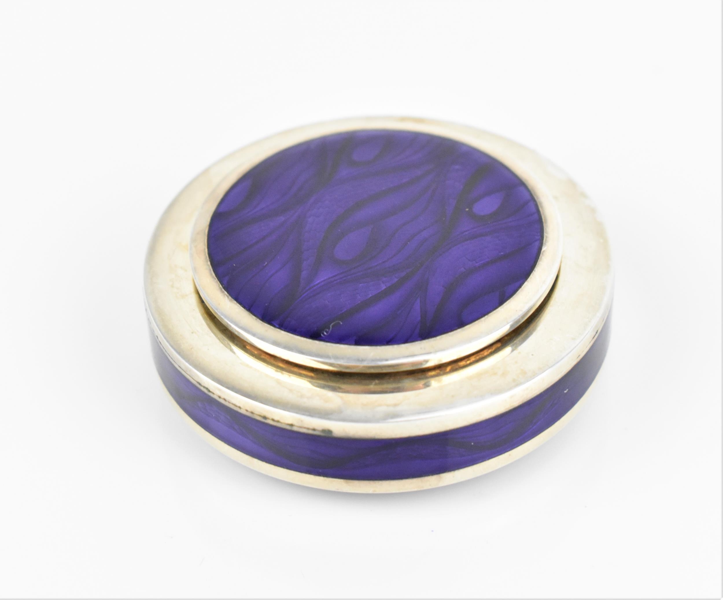 A modern British silver and enamel pill box, of circular form with purple wave pattern to the