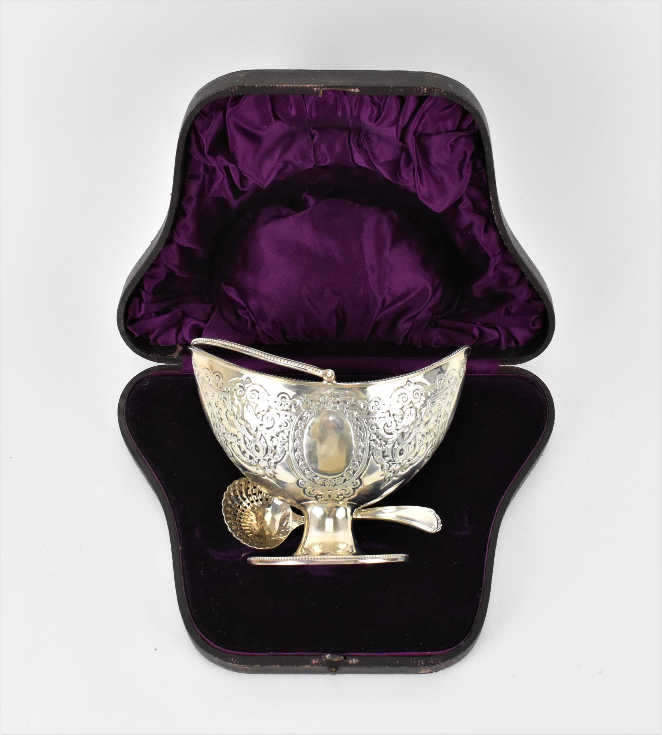 A cased Victorian silver sugar basket, London 1880, of oval form with swing handle, beaded rim and