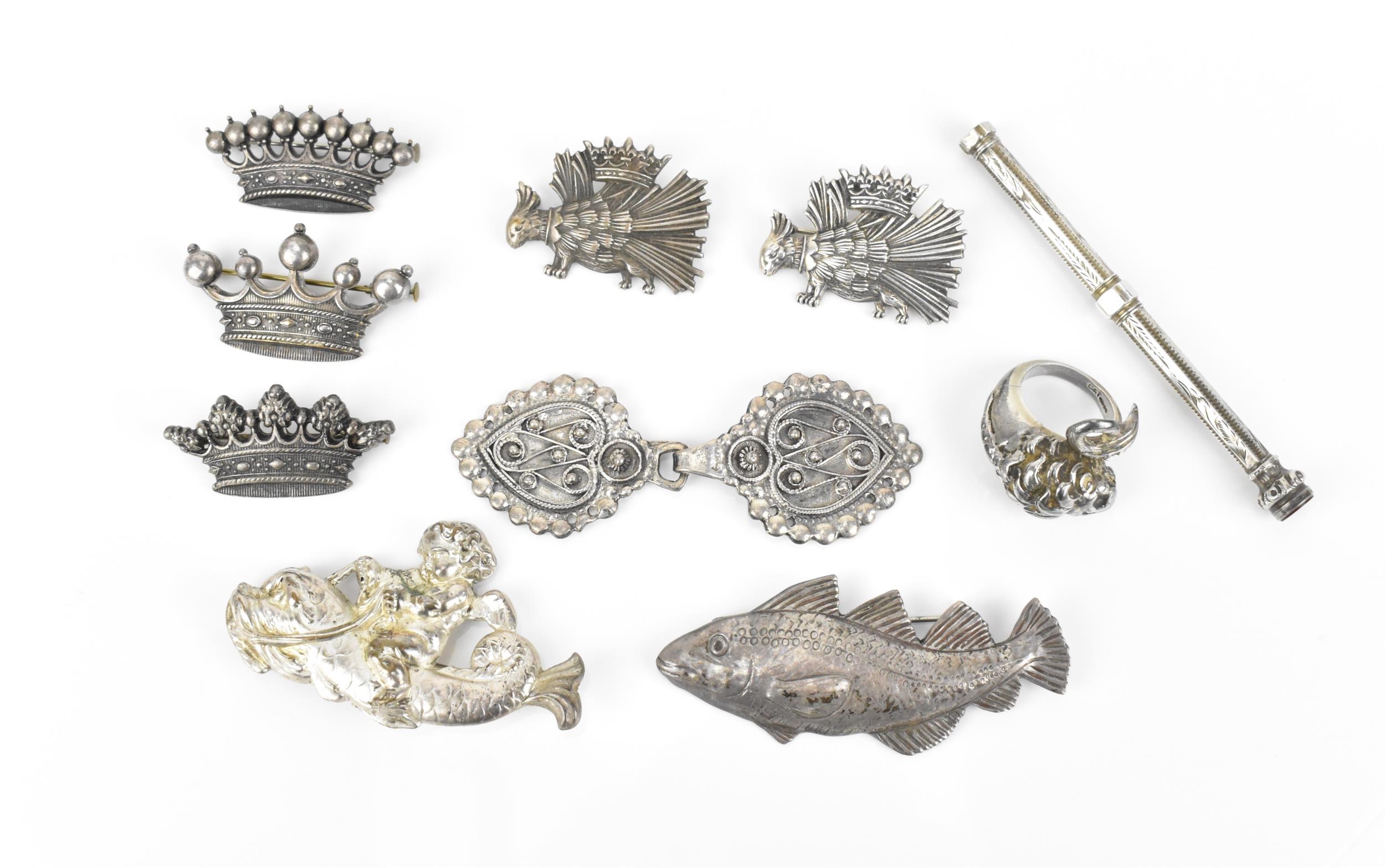 A small collection of metal brooches, to include a silver model of a fish, three white metal crown