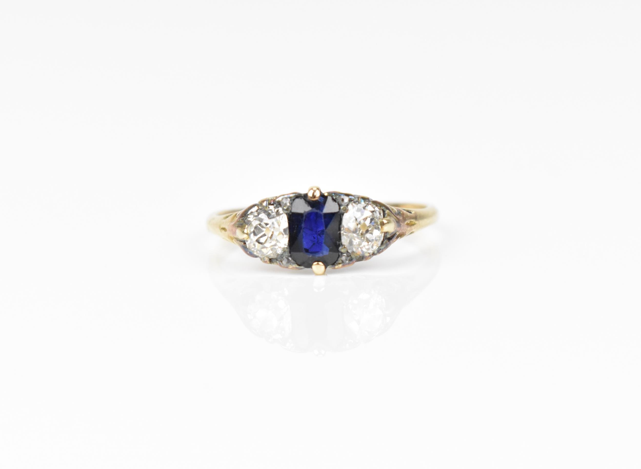 A yellow metal, blue sapphire and diamond dress ring, with central octagon cut sapphire flanked with