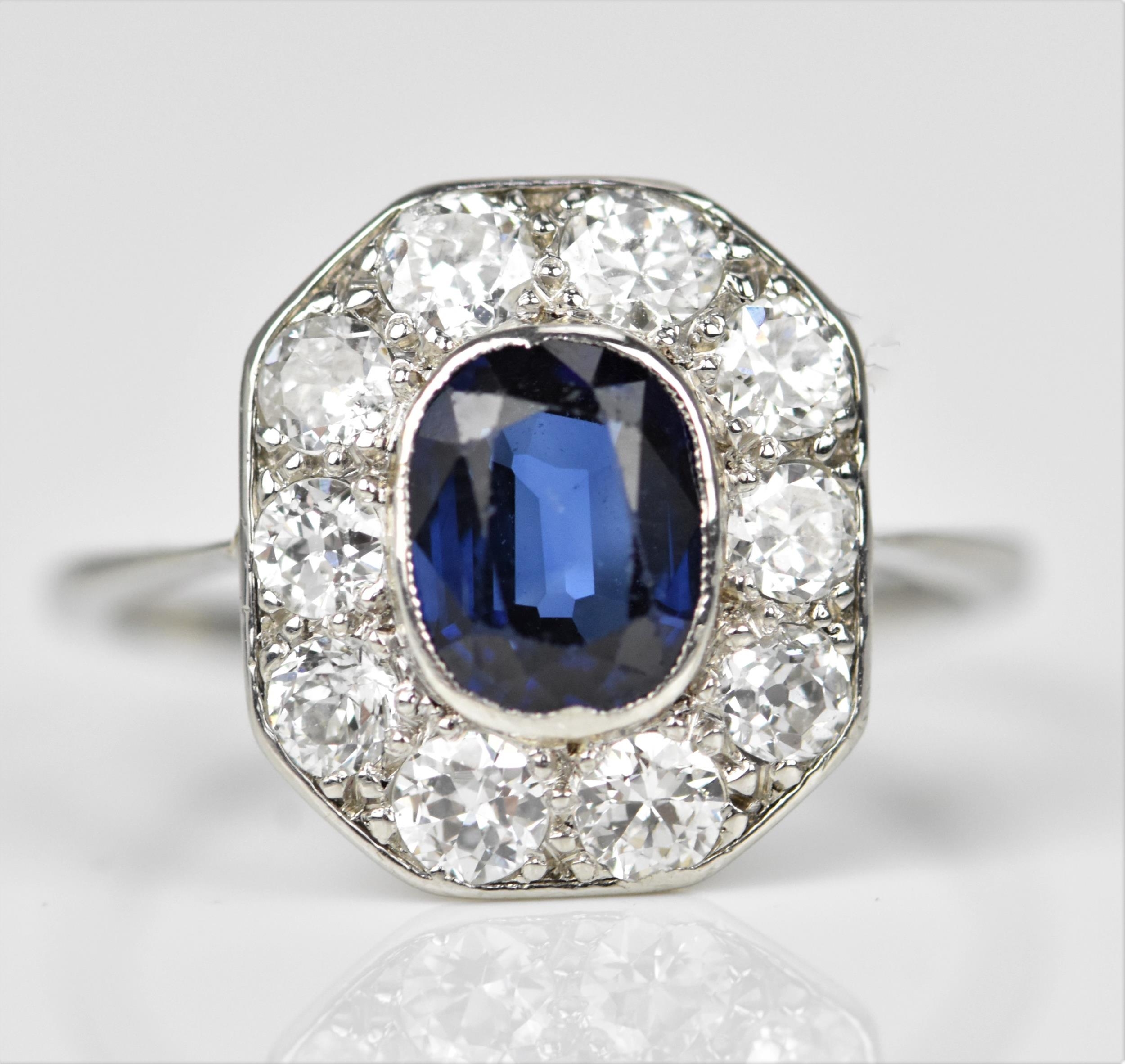 An Art Deco platinum, diamond and sapphire dress ring, the central deep blue sapphire in a