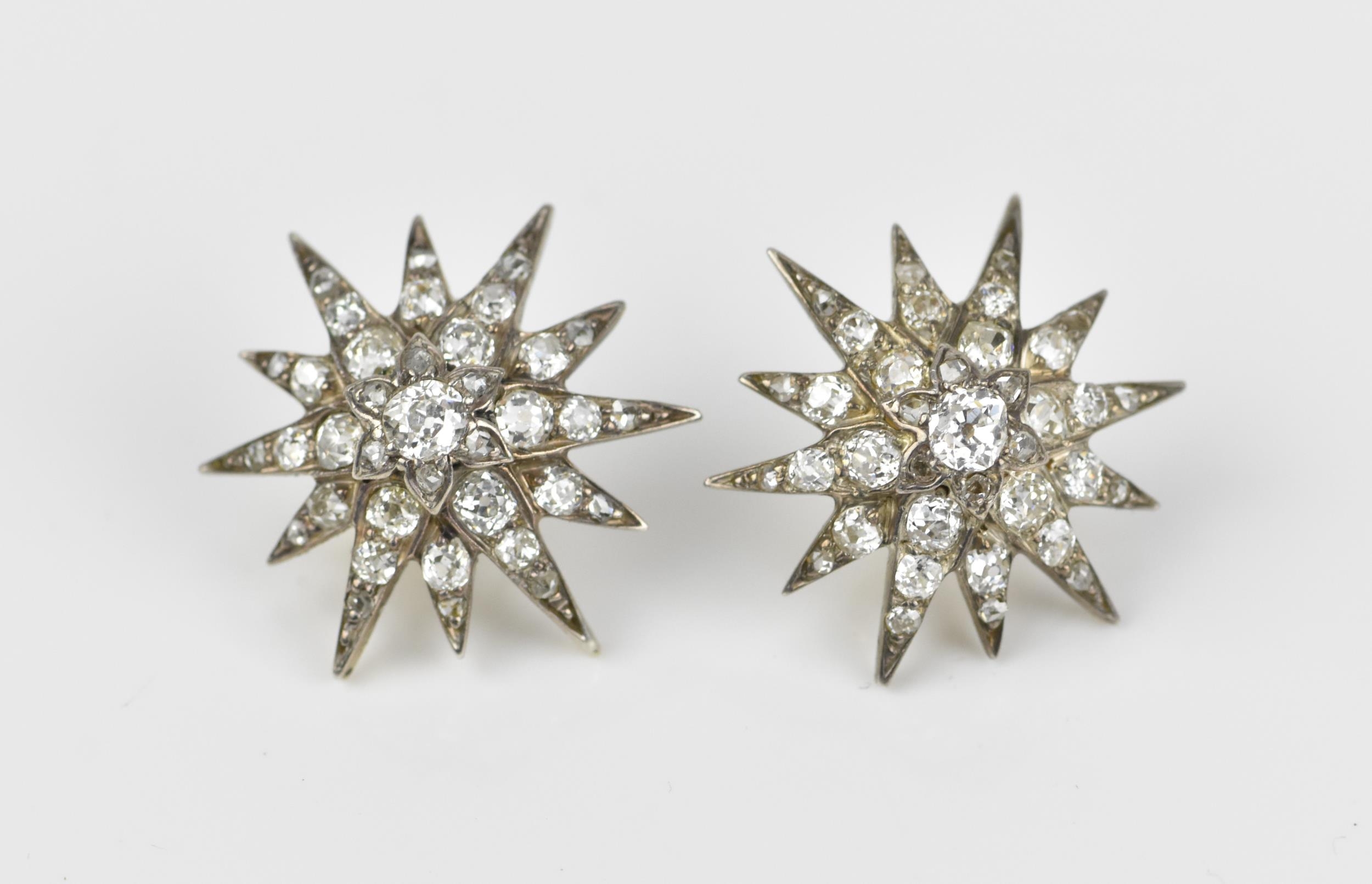 A pair of early 20th century white metal and diamond starburst earrings, set with old mine cut