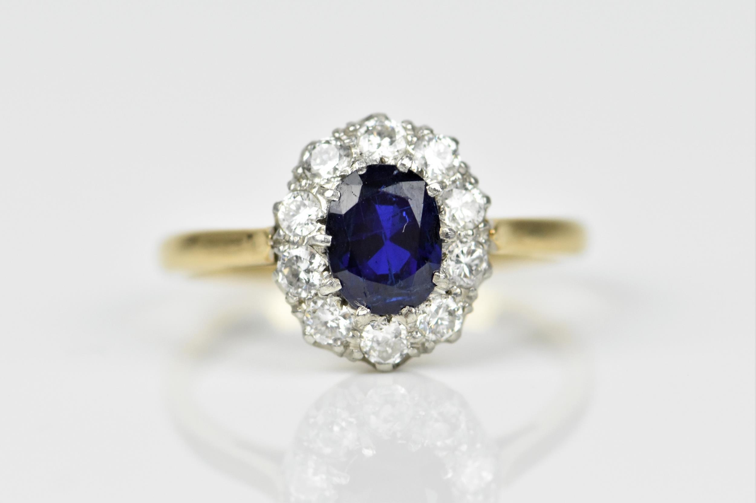 An 18ct yellow gold, sapphire and diamond cluster ring, with central oval cut blue sapphire in a
