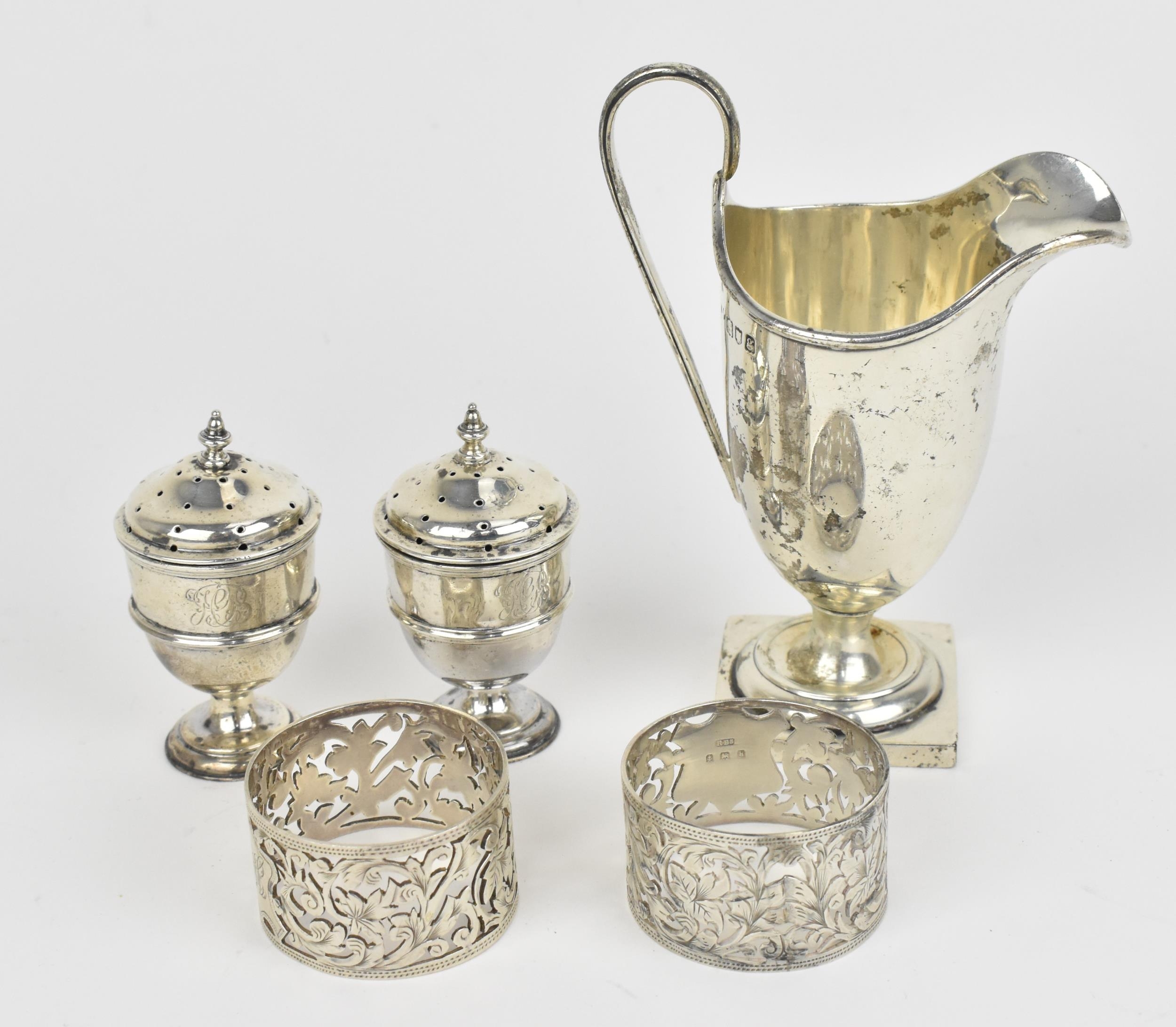 A small collection of silver, to include an Edwardian silver milk jug, a pair of Victorian pepper