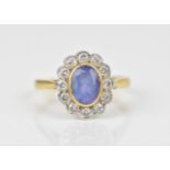 An 18ct yellow gold, white metal, pale blue stone and diamond halo dress ring, the central oval