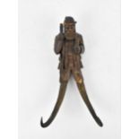 A Black Forest chamois antler whip hook, with figural carving of a hunter, his legs ending in