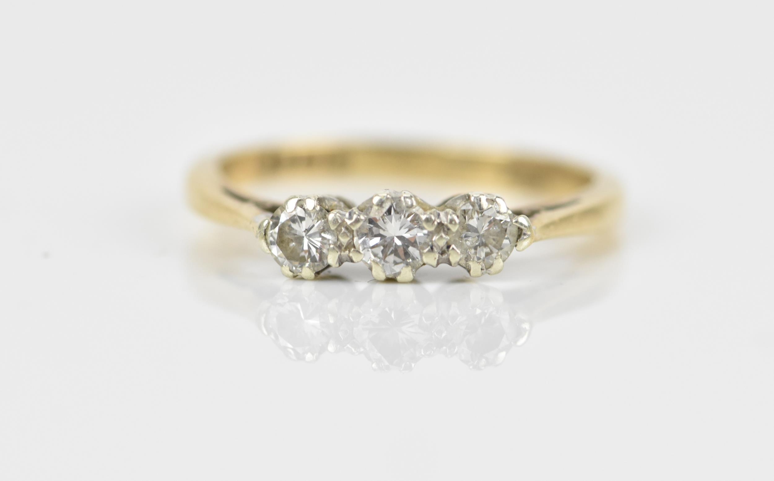 A 9ct yellow gold and three stone diamond ring, all three brilliant stones set in white metal with