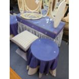 A purple lined top dressing table with curtains below together with a pair of circular topped