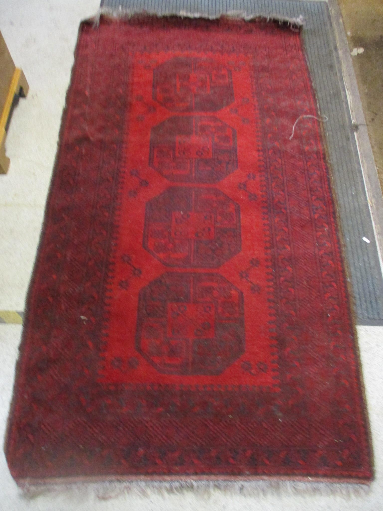 An Afghan handwoven rug, four central elephant gulls on a red ground, triple guard border 205cm x