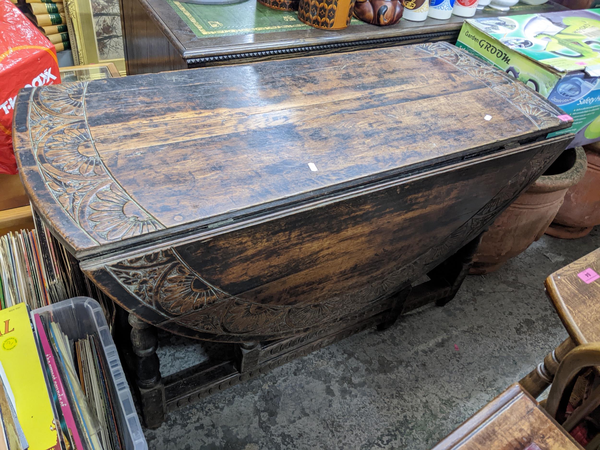 A Victorian carved oak gateleg table, the top with a band of stylised floral decoration, on turned