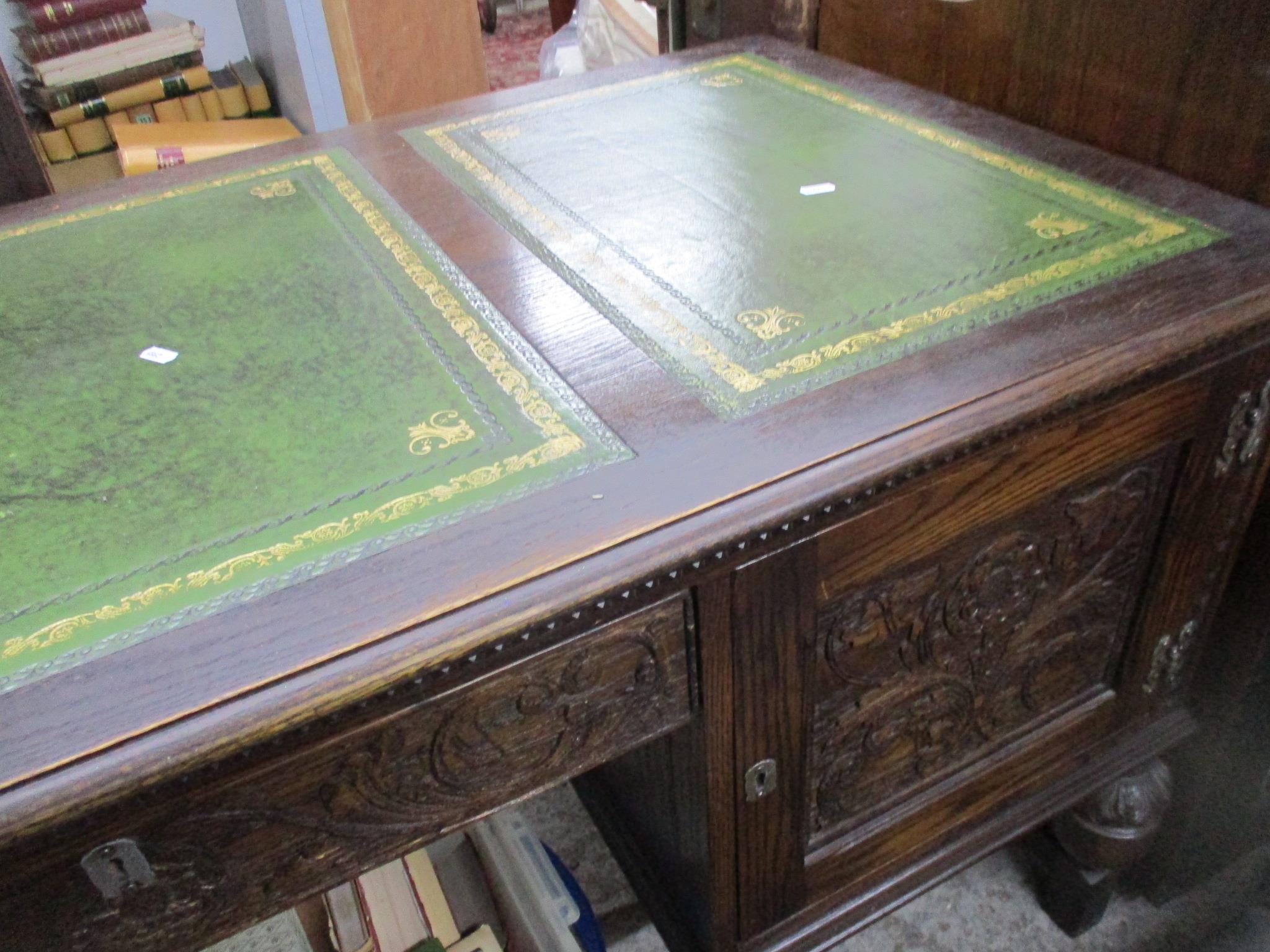 A mid to late 20th century oak kneehole writing desk, the top with three panels of green leather