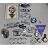 A collection of car badges to include BWM Mercedes, Ford, Austin and others along with a