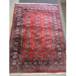 A Pakistan handwoven red ground rug decorated with elephant gulls and geometric devices,