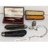 A mixed lot to include a cased 9ct gold and amber cheroot holder, two pen knives, silver thimble,