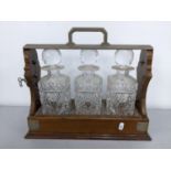 An early 20th century walnut three decanter Tantalus, 32h x 38w