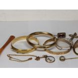 A mixed lot of jewellery to include three gold plated bangle bracelets, a stick pin, a chain link